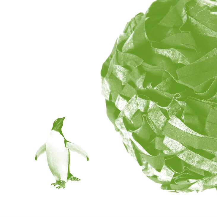 With a green filter, a penguin looks up at what looks like a huge ball of crumbled paper rolling towards it.